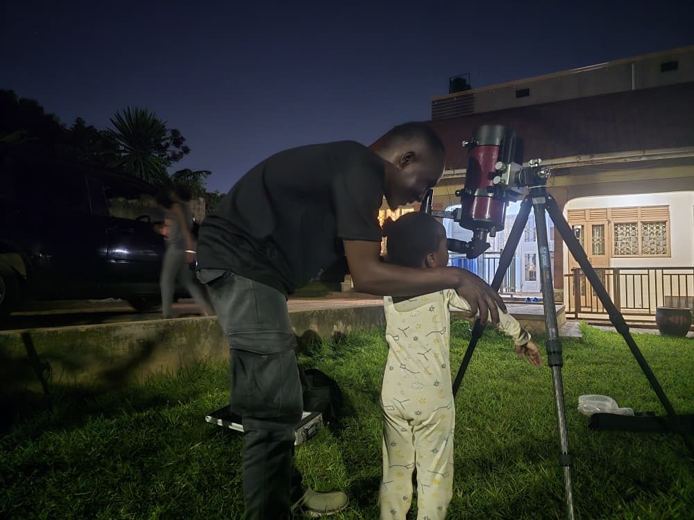 A UAS member guiding a child through a telescope at night